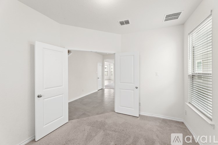 A spacious, empty room with white walls and carpeted floor.