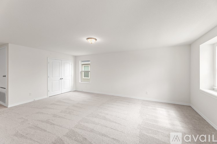 A spacious room with a carpeted floor and white walls.
