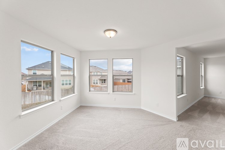 A spacious empty room with a carpeted floor and large windows.