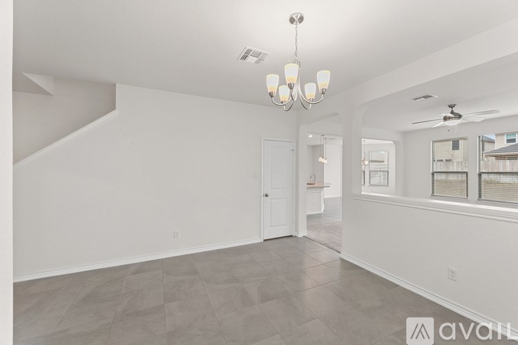 A spacious, empty room with a chandelier and a ceiling fan.