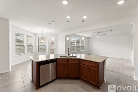A modern kitchen with a center island and pendant lights.