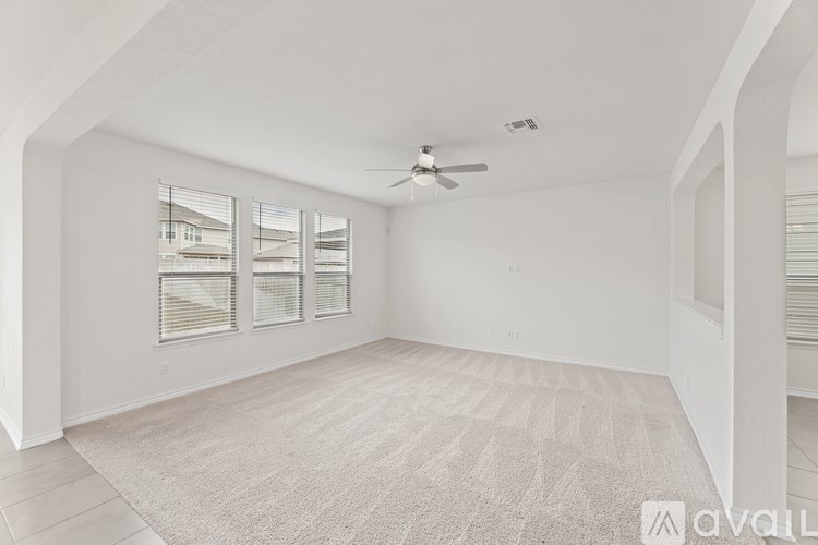 A spacious room with a carpeted floor and a ceiling fan.