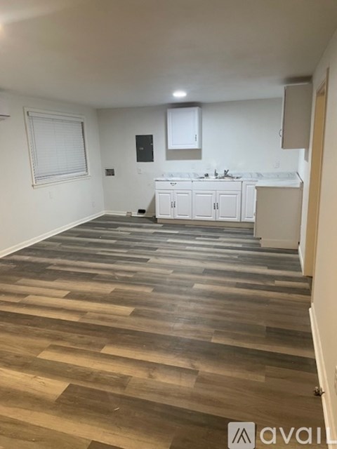 A kitchen area with wooden flooring and white cabinets.
