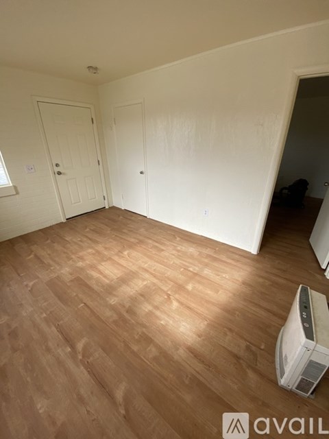 A room with wooden flooring and a wall-mounted air conditioner unit.