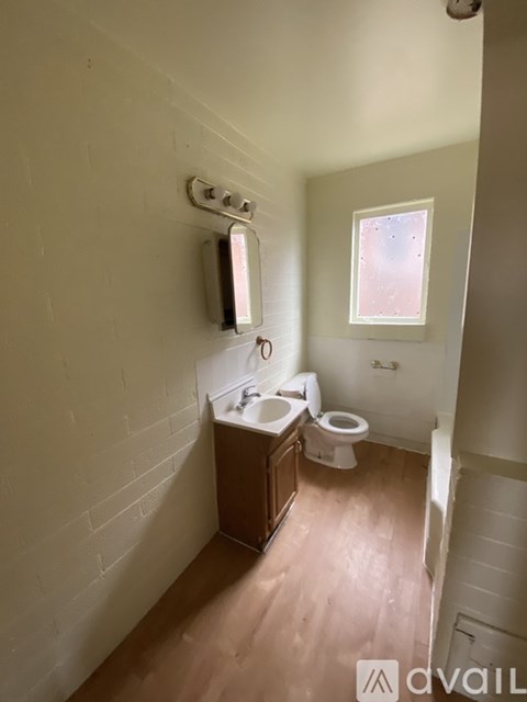 A bathroom with a toilet, sink, and mirror.
