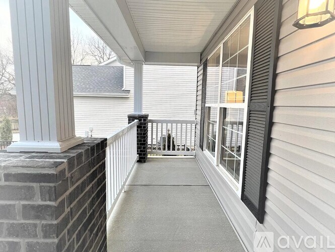 A porch with a black railing and a brick pillar.