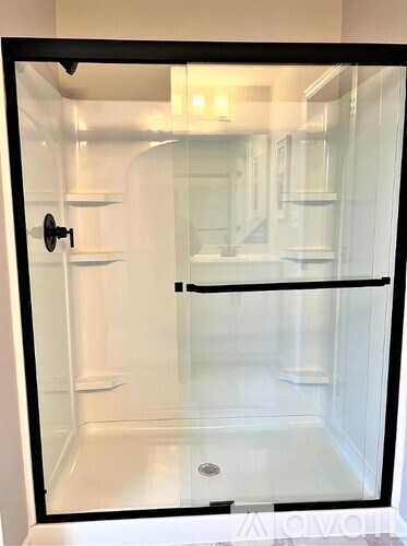 A glass shower stall with a black frame and a white door.