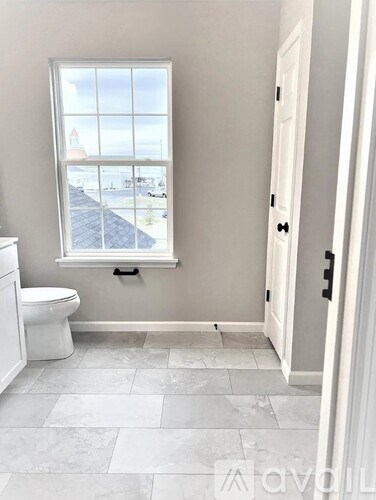 A bathroom with a toilet, a window and a door.