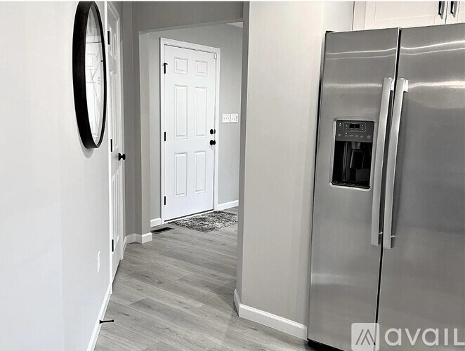A modern kitchen with a stainless steel refrigerator and a white door.
