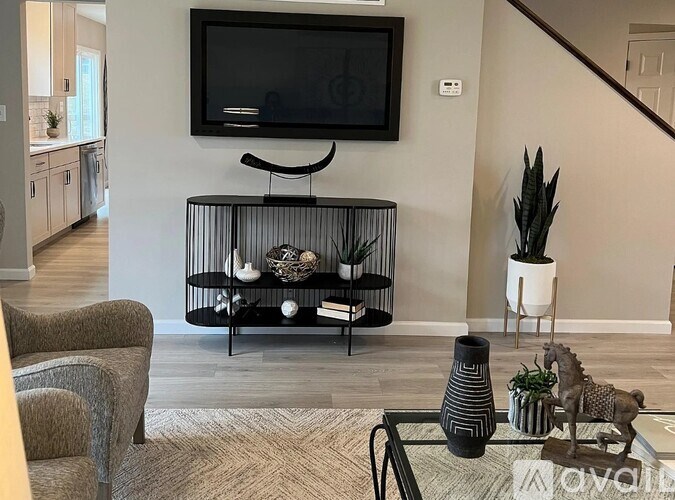 A living room with a television, a chair, a coffee table, and a plant.