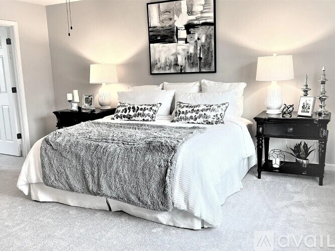 A bedroom with a bed, two nightstands, and a painting on the wall.