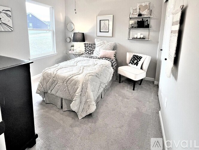 A bedroom with a bed, chair, and shelves.