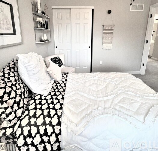 A bed with a black and white comforter is in the foreground of the image.