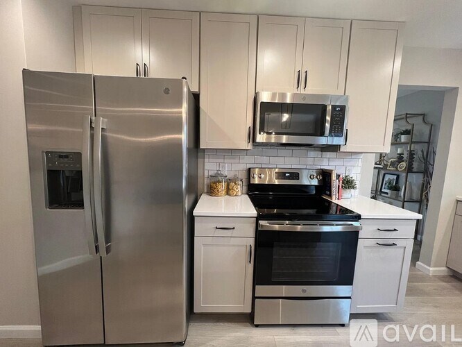 A modern kitchen with a stainless steel refrigerator and white cabinets.