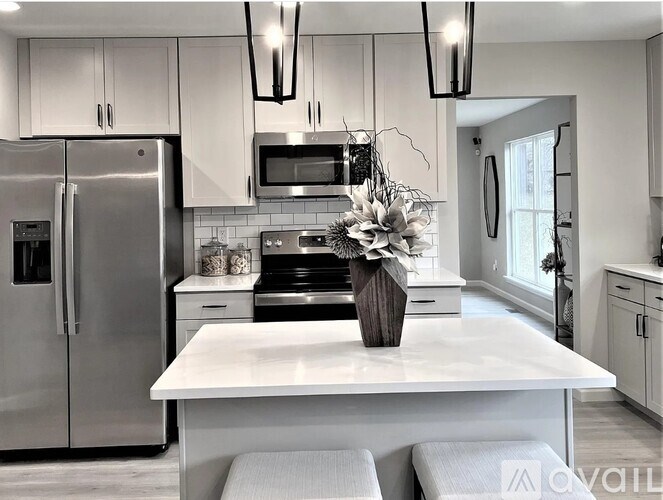 A modern kitchen with a white island and stainless steel appliances.