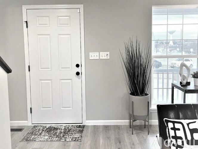 A white door with a black handle and a black and white chair in front of it.