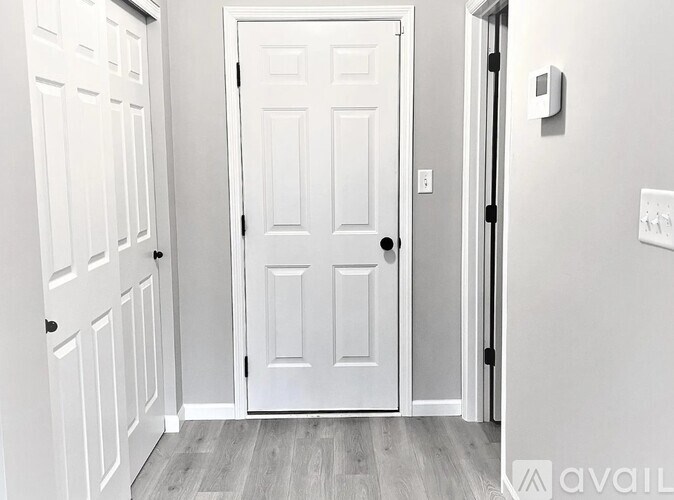 A white door is in a room with a wooden floor.