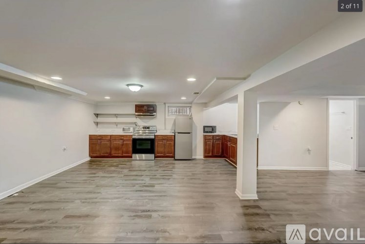 A spacious living room with a kitchen in the background and a large empty floor.