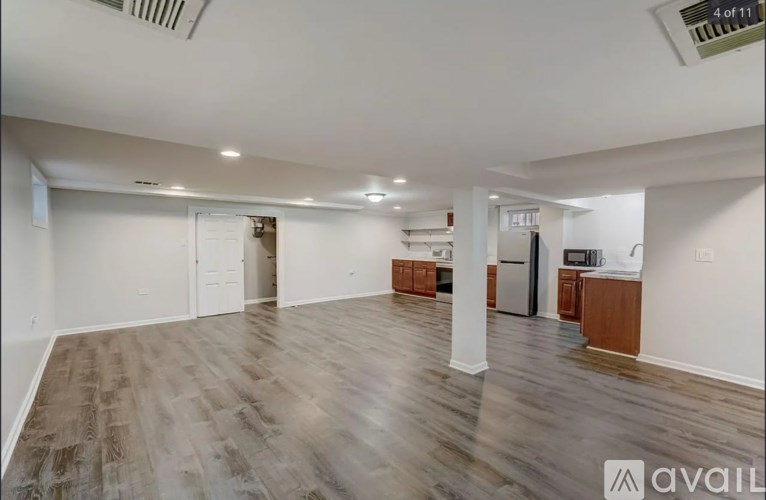 A spacious room with wooden flooring and white walls.