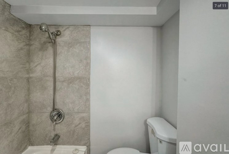 A bathroom with a toilet, a shower head and a shower head.