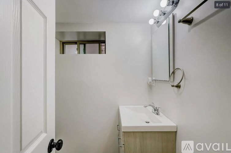 A bathroom with a sink, mirror, and lighting fixture.