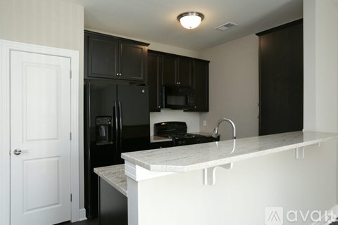 A kitchen with black cabinets and a white counter.