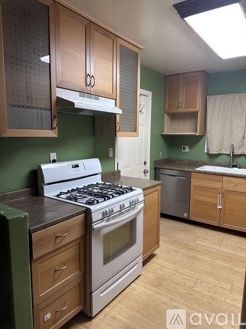 A kitchen with a white stove and wooden cabinets.