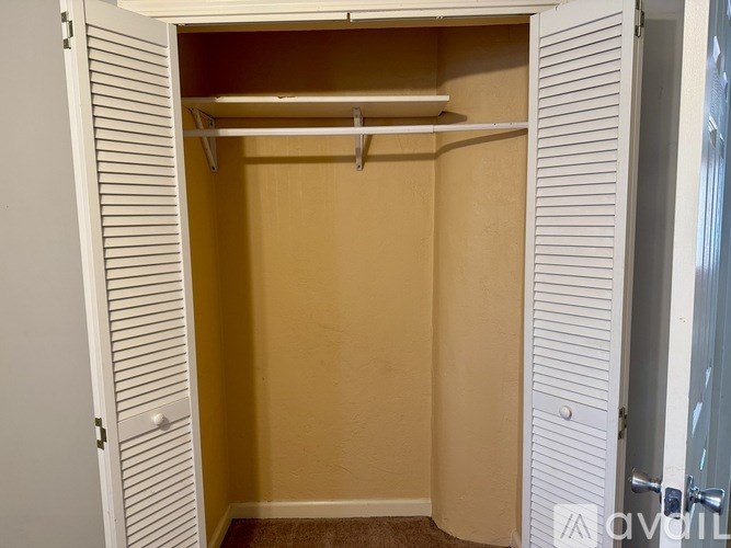 A white closet with a shelf and a white door.