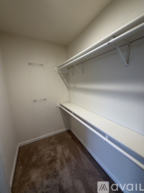 A white closet with a carpeted floor and a white bench.