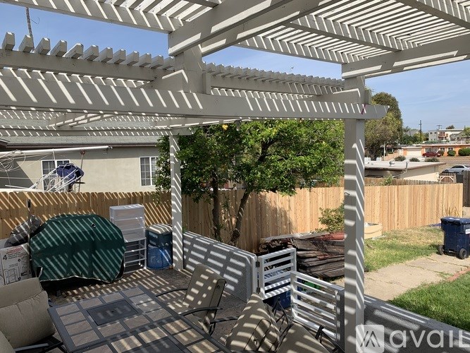 A patio with a white pergola and a grey couch.
