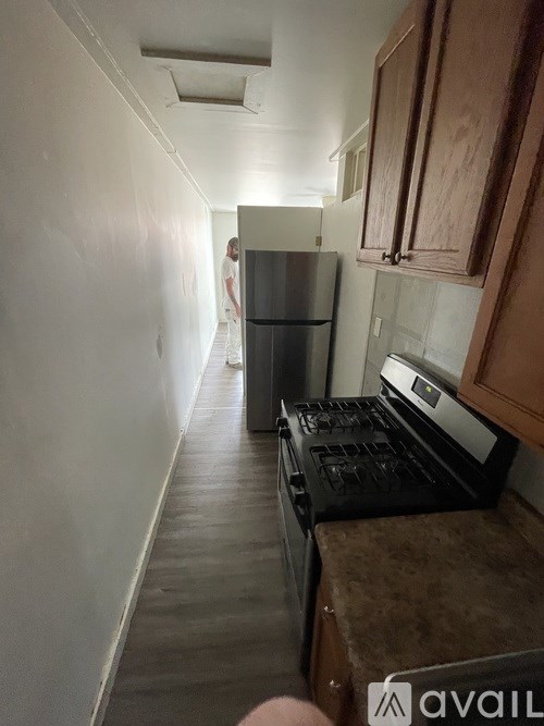 A kitchen with a refrigerator, oven, and a person in the background.