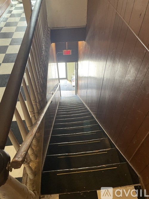 A staircase with a checkered floor and a wooden handrail.