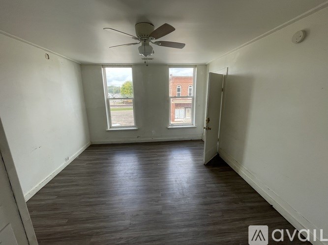 A room with a ceiling fan and wooden flooring.