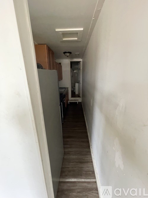 A long hallway with a white wall on the left and a brown cabinet on the right.