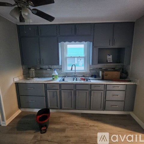A kitchen with grey cabinets and a fan on the ceiling.