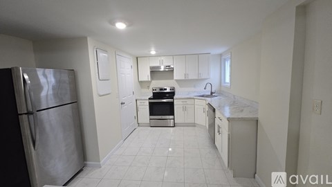 A kitchen with white cabinets and a stainless steel refrigerator.