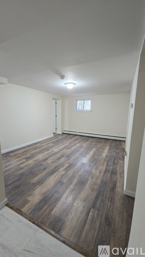 A room with wooden flooring and a window.