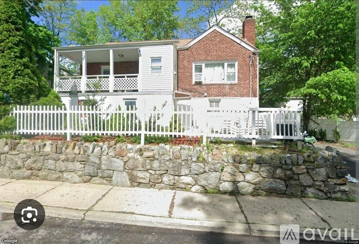 A house with a white fence and a stone wall in front.