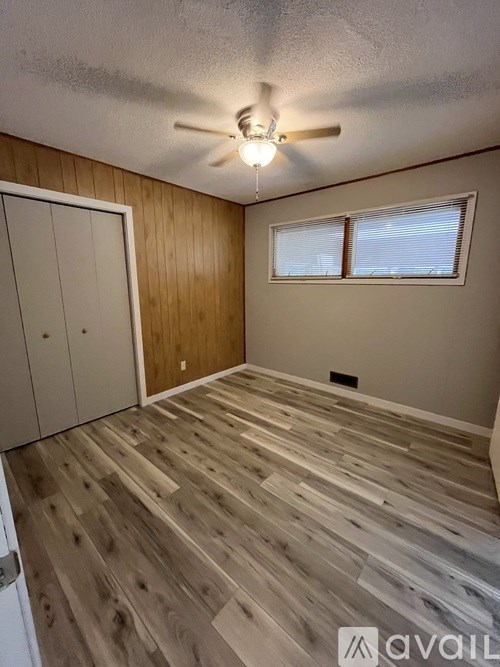 A room with wooden flooring and a ceiling fan.