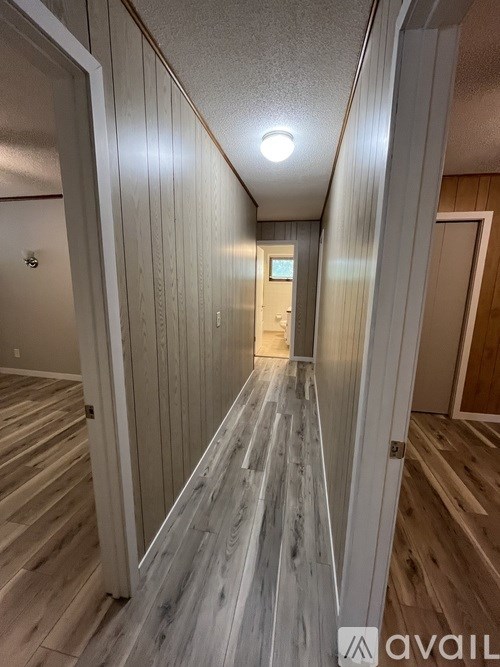 A long hallway with wood flooring and white walls.