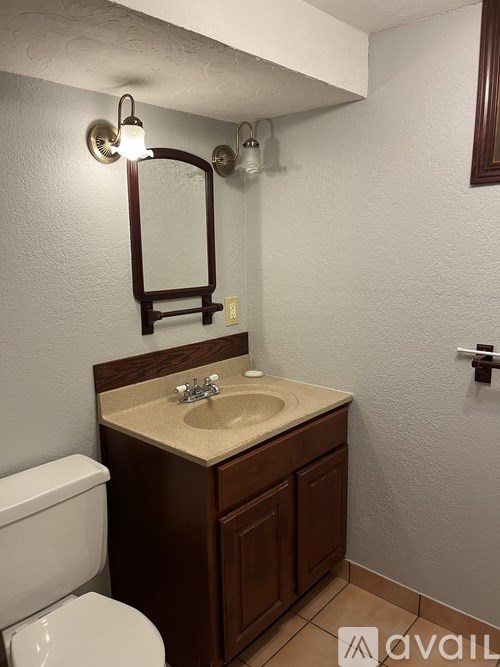 A bathroom with a toilet, sink, and mirror.