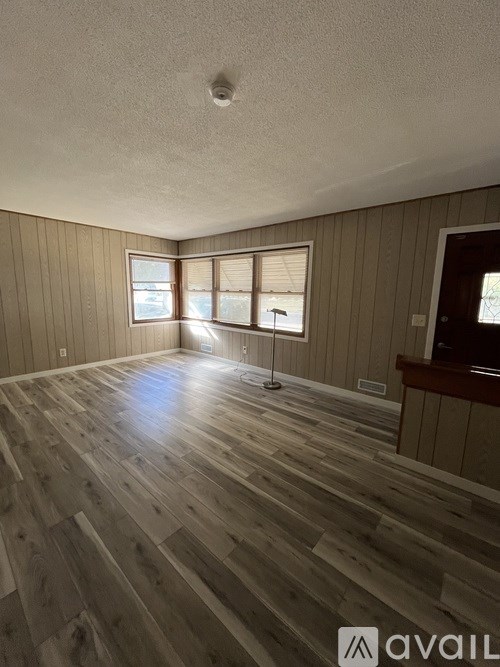 A room with wooden flooring and a window with blinds.