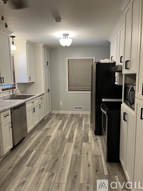 A kitchen with white cabinets and a black refrigerator.