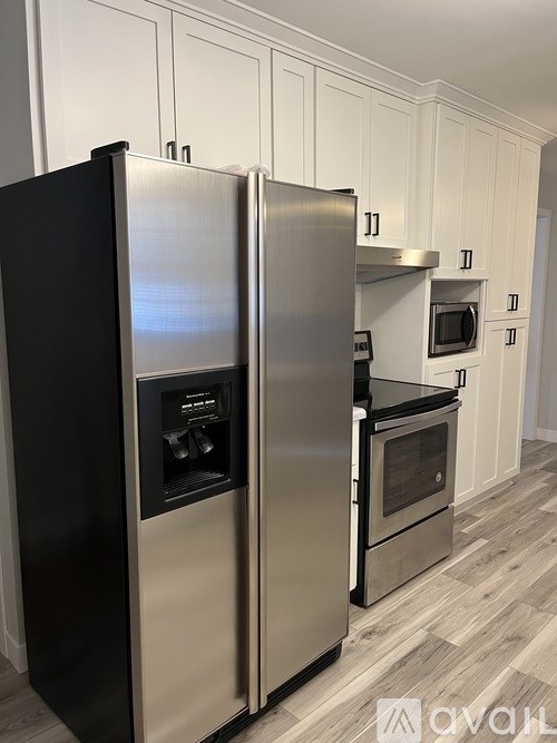 A modern kitchen with a black fridge and stainless steel appliances.