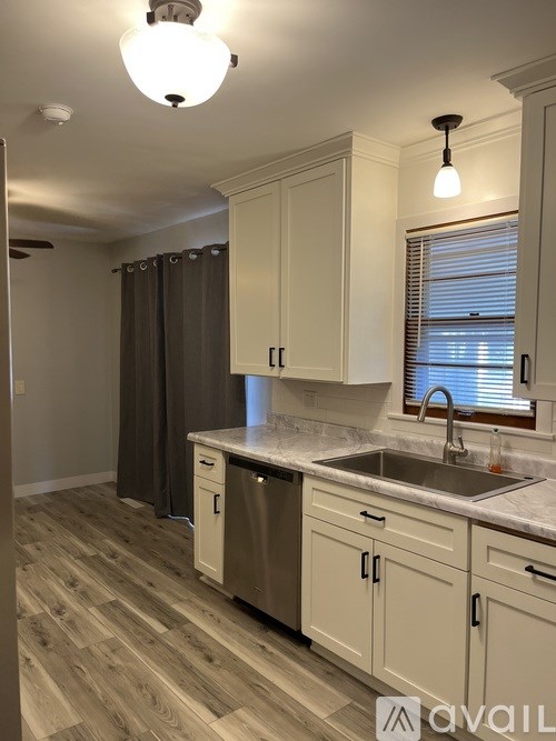 A kitchen with wooden floors and white cabinets.