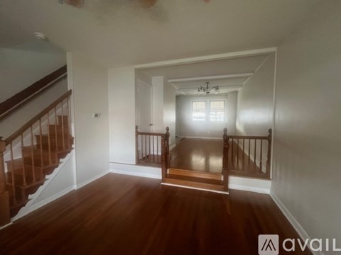 A room with wooden floors and a staircase leading to another room.