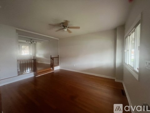 A room with a ceiling fan and wooden floors.