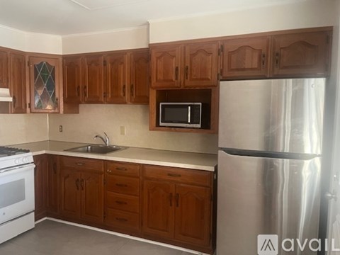 A kitchen with wooden cabinets and a stainless steel refrigerator.