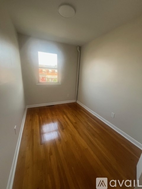 A room with wooden floors and a window showing a view of a building.