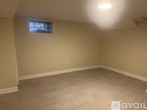 A room with beige walls and a window with blinds.
